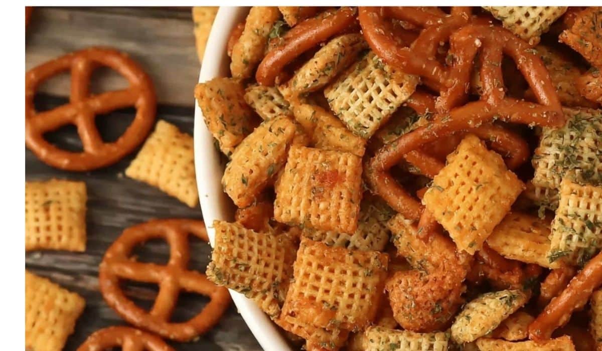 Cheesy ranch Chex Mix in a large white bowl with pretzels and cheddar crackers